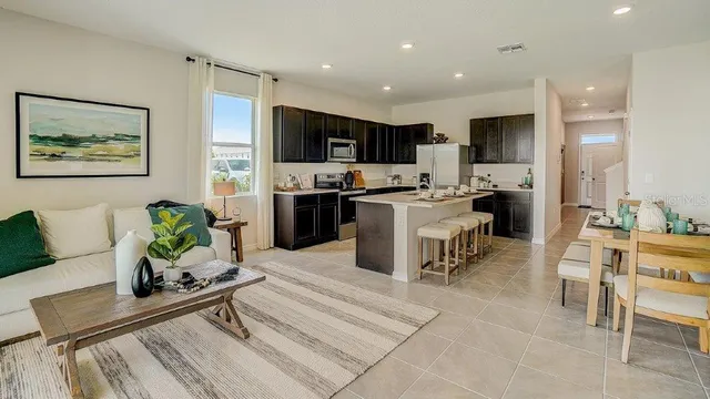 a living room with stainless steel appliances furniture a rug kitchen view and a kitchen island