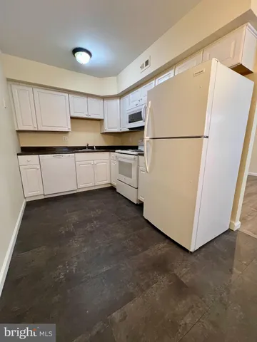 a kitchen with white cabinets and white appliances