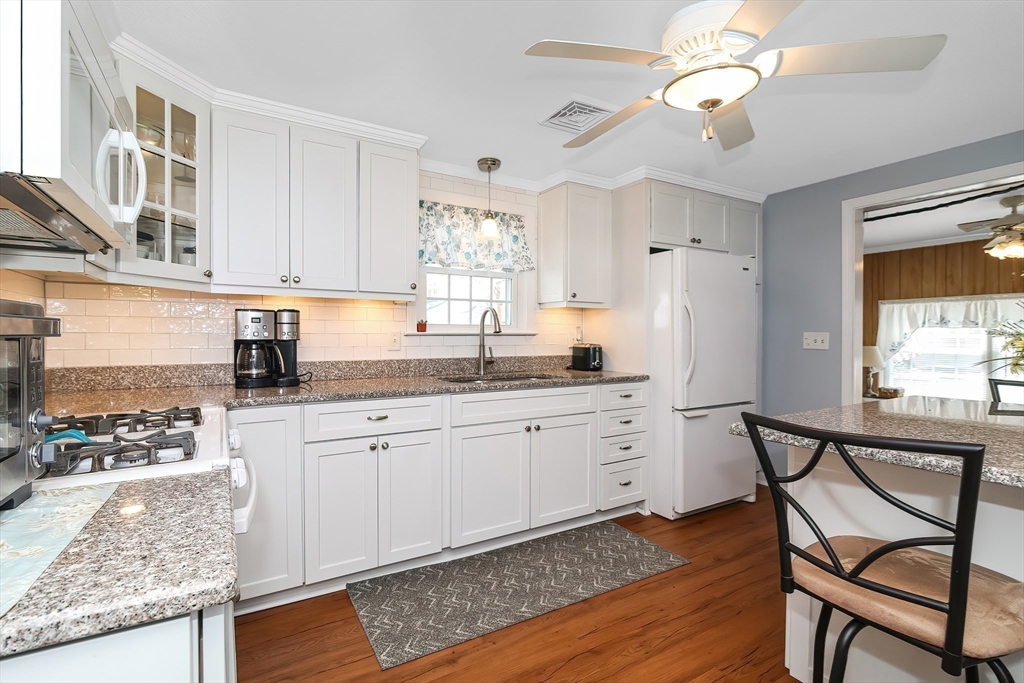 60 Security Street Barnstable, MA 02601 - Photo 12 of 32 a kitchen with granite countertop white cabinets stainless steel appliances a sink and a window