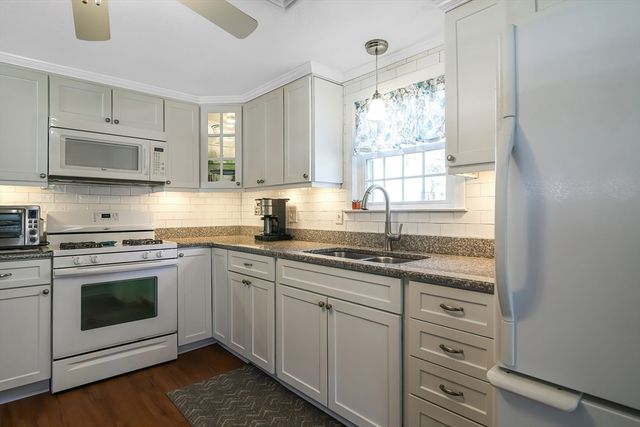 a kitchen with granite countertop white cabinets window and stainless steel appliances