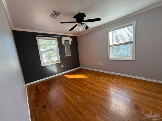 a view of empty room with wooden floor and fan