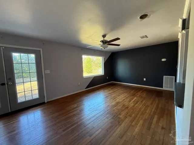 a view of an empty room with window and wooden floor