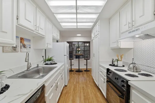 a kitchen with stainless steel appliances granite countertop a sink a stove and a wooden floors