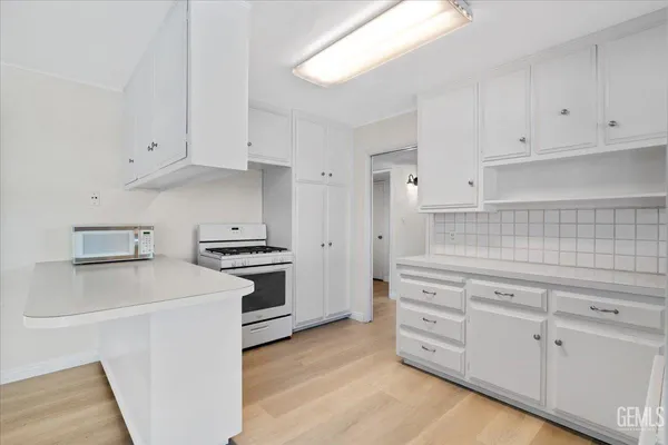 a kitchen with granite countertop white cabinets and white appliances