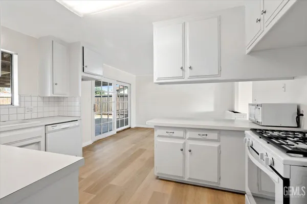 a kitchen with granite countertop white cabinets and white appliances
