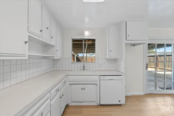 a kitchen with white cabinets and window