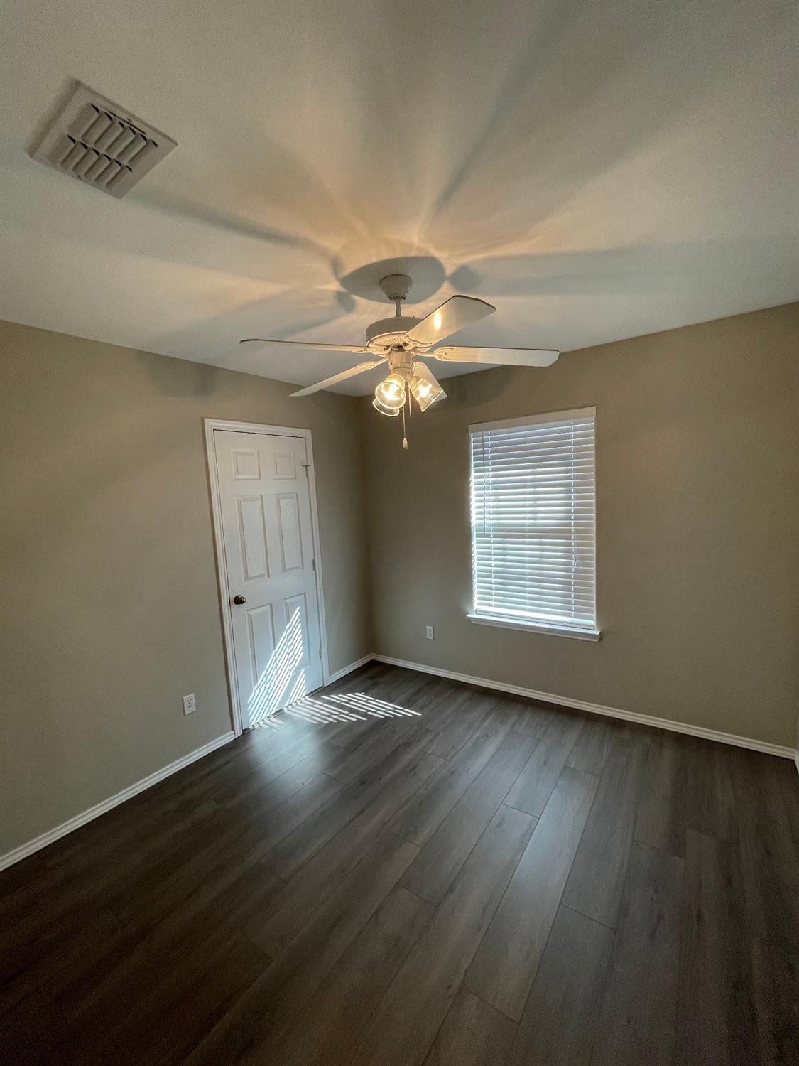 1903 99th Place Lubbock, TX 79423 - Photo 5 of 10 an empty room with wooden floor chandelier fan and windows