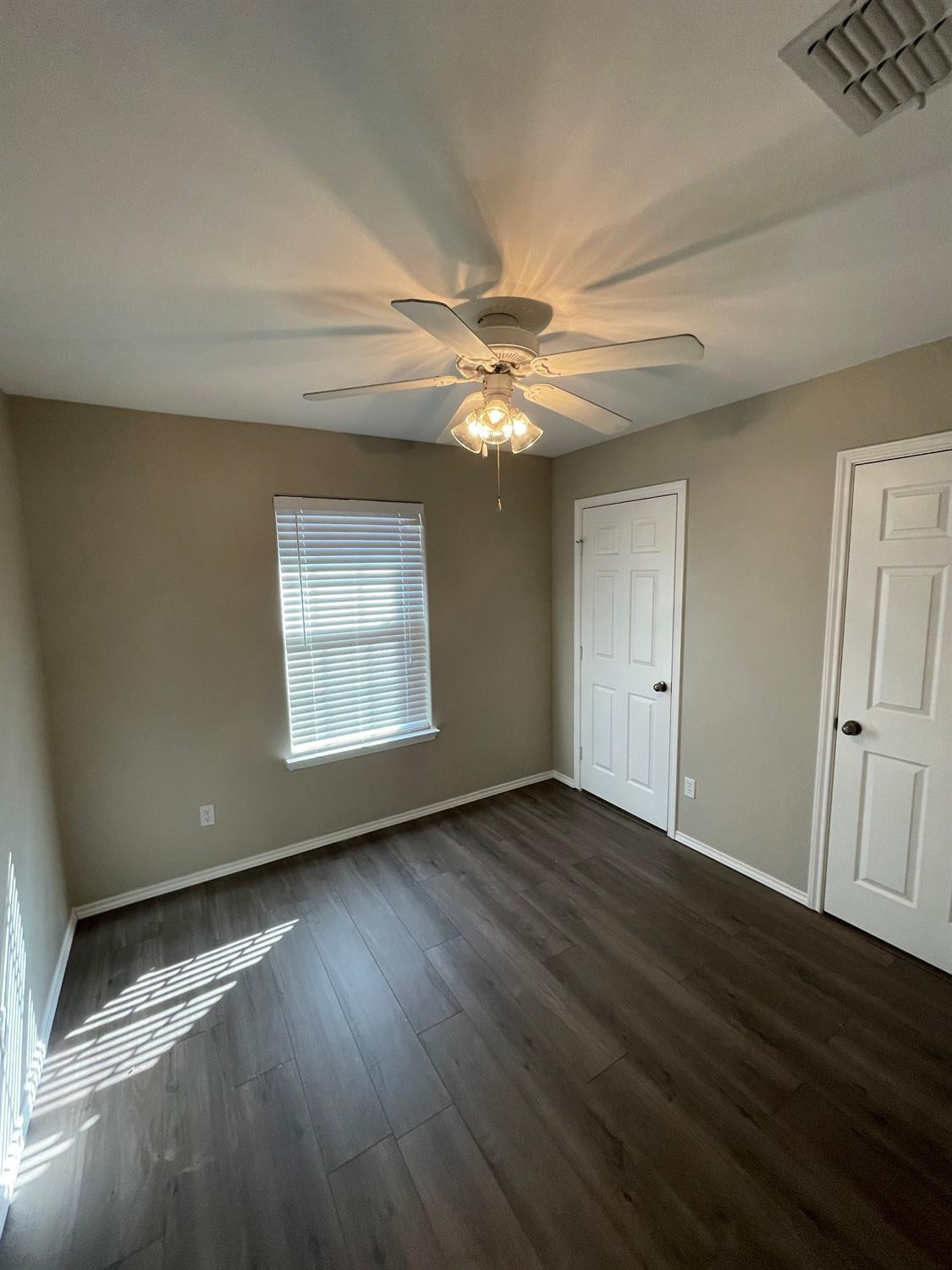 1903 99th Place Lubbock, TX 79423 - Photo 7 of 10 an empty room with wooden floor chandelier fan and windows