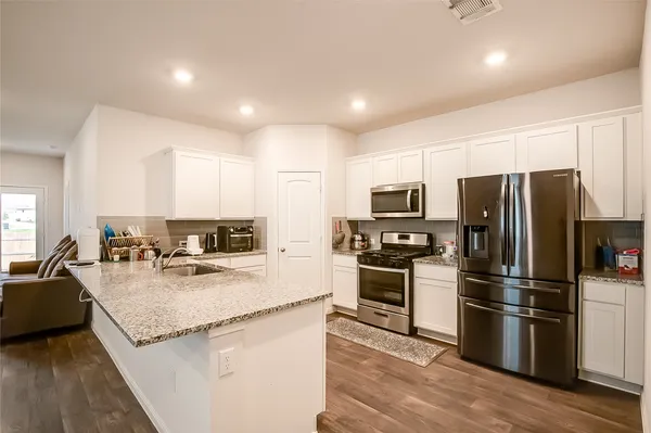 a kitchen with granite countertop a refrigerator stove microwave and sink