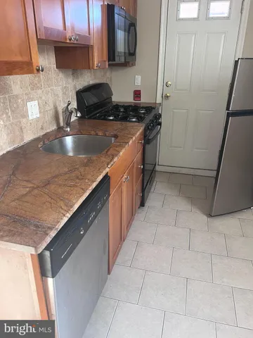 a kitchen with stainless steel appliances granite countertop a sink a stove and a microwave