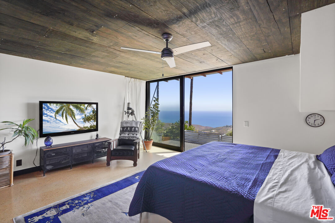 26335 Lockwood Road Malibu, CA 90265 - Photo 13 of 39 a bedroom with a balcony a bed and a flat screen tv