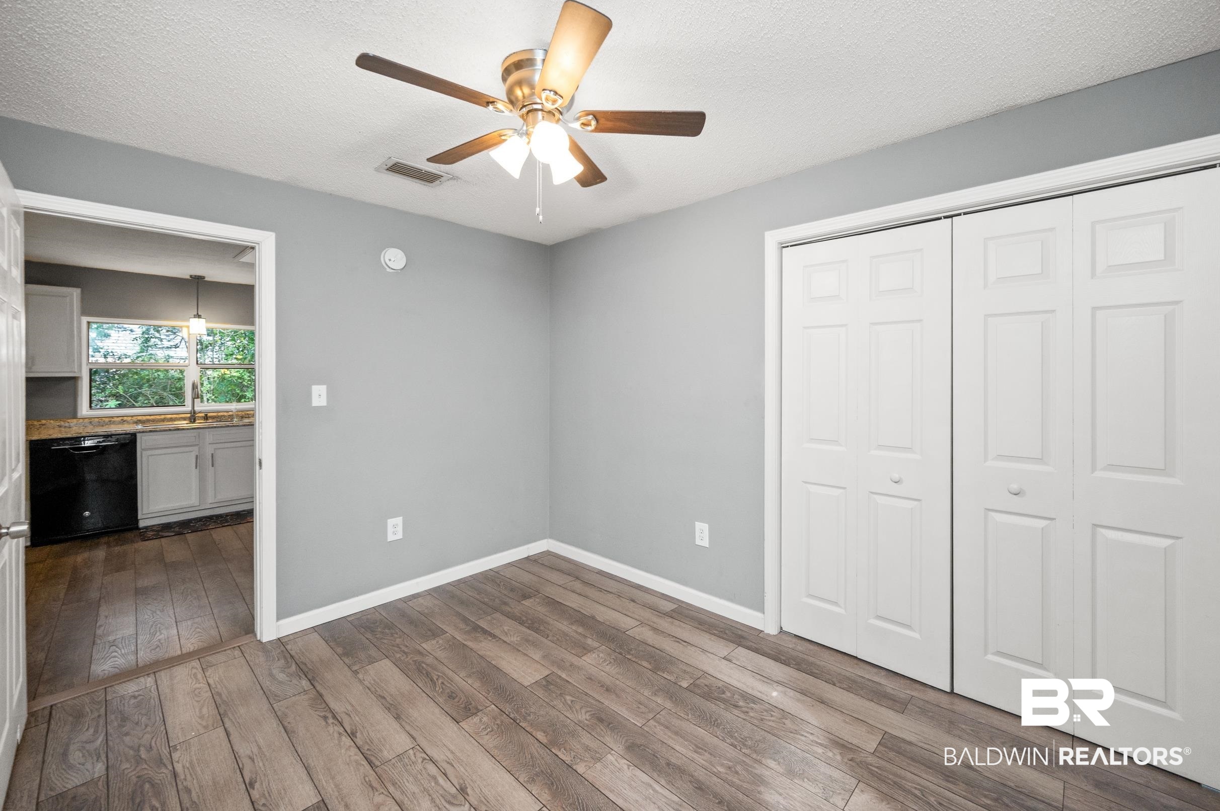 906 North Cedar Street Foley, AL 36535 - Photo 10 of 24 Unfurnished bedroom with a textured ceiling, wood-type flooring, ceiling fan, and a closet