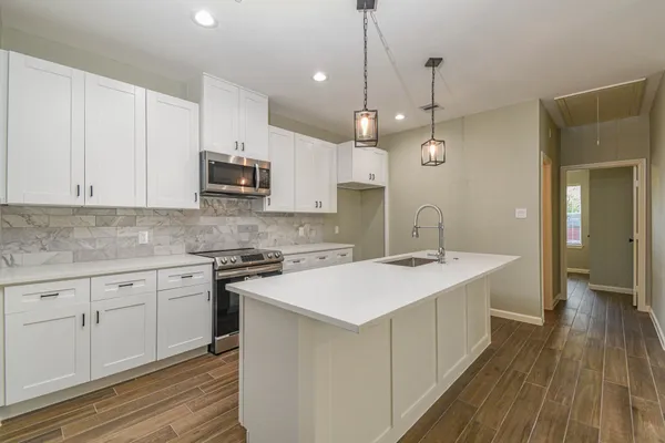a kitchen with kitchen island a sink stove and wooden floor