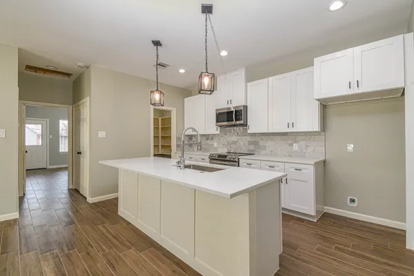 a kitchen with kitchen island a sink stove and wooden floor