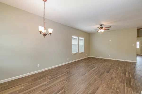 a view of an empty room with a window and wooden floor