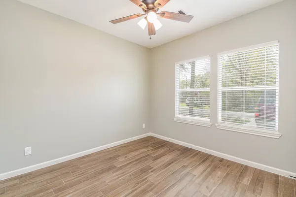a view of an empty room with wooden floor and a window