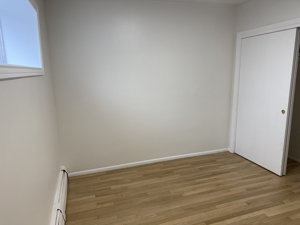 115 Grove Street, Unit 1 Boston, MA 02132 - Photo 12 of 15 a view of an empty room with wooden floor and a window
