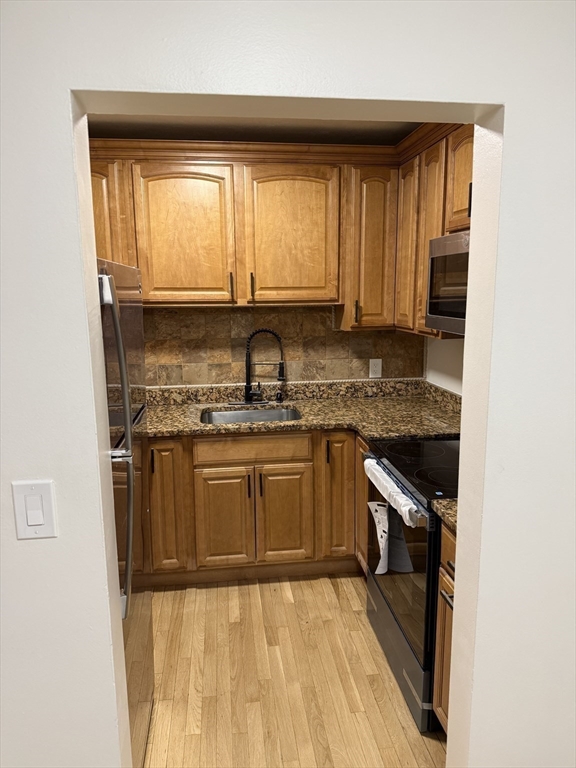 115 Grove Street, Unit 1 Boston, MA 02132 - Photo 5 of 15 a kitchen with stainless steel appliances granite countertop a stove a sink and a microwave