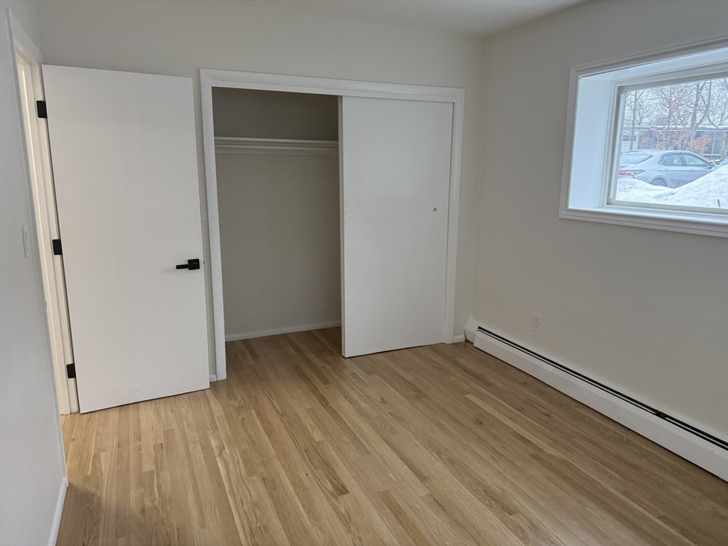 115 Grove Street, Unit 1 Boston, MA 02132 - Photo 8 of 15 a view of an empty room with wooden floor and a window