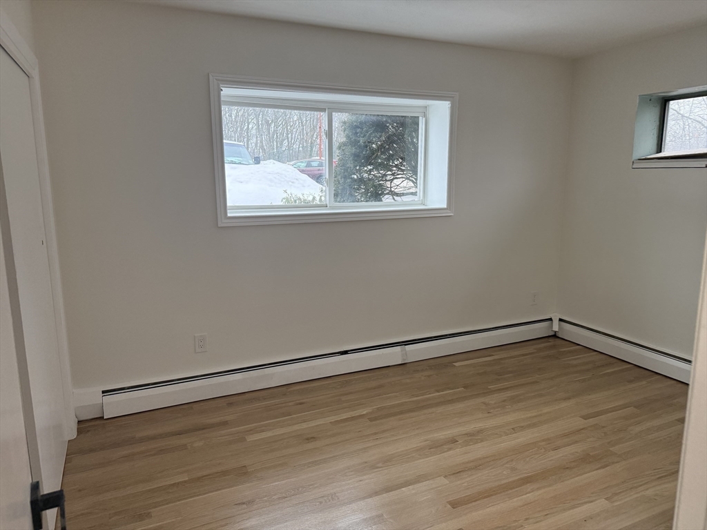 115 Grove Street, Unit 1 Boston, MA 02132 - Photo 10 of 15 a view of an empty room with wooden floor and a window
