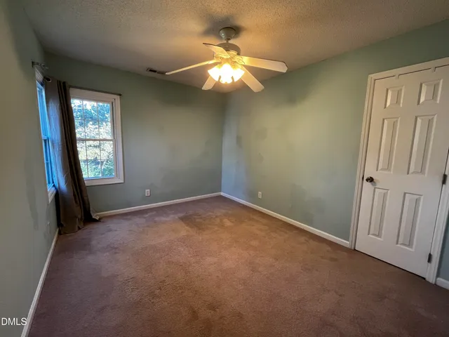 an empty room with windows and fan