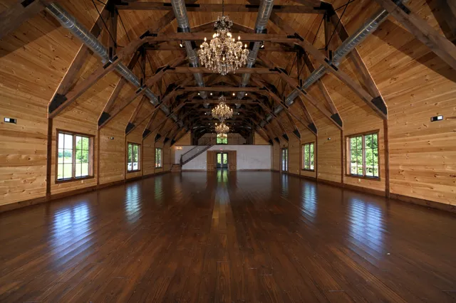 a hallway with wooden floors with couches and chandelier