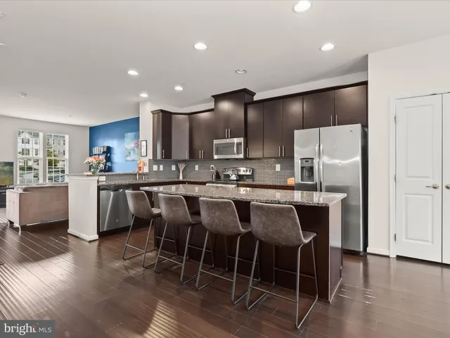 a kitchen with stainless steel appliances a dining table chairs refrigerator and microwave