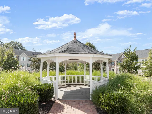 a view of a white house next to a yard with potted plants