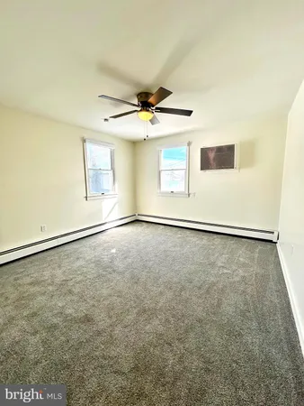 an empty room with windows and fan