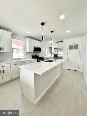 a large white kitchen with a window and stainless steel appliances