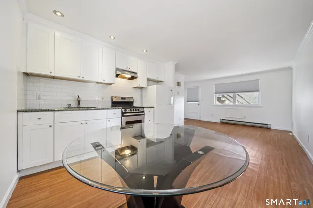 a kitchen with stainless steel appliances granite countertop a sink a stove a dining table and chairs