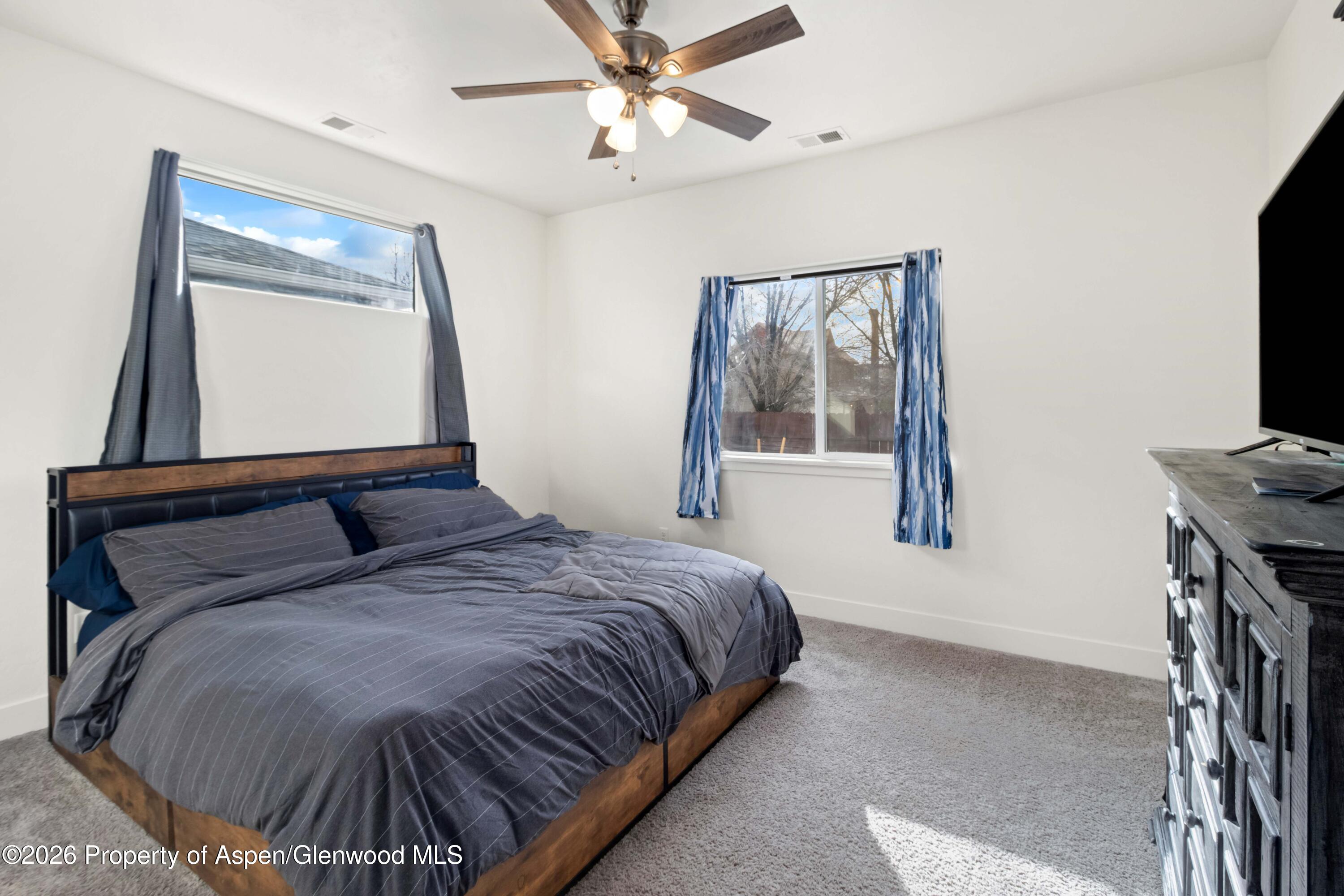 1671 East 17th Circle Rifle, CO 81650 - Photo 10 of 25 a bedroom with a bed and a flat tv screen on dresser
