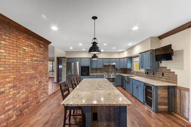 a kitchen with stainless steel appliances granite countertop wooden floor sink stove and wooden floor