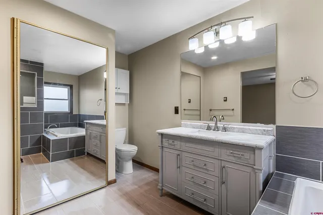 a bathroom with a double vanity sink a toilet and a mirror