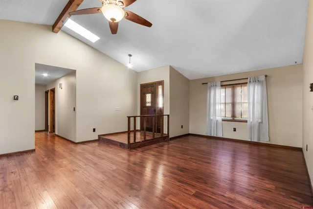 a view of an empty room with window and wooden floor