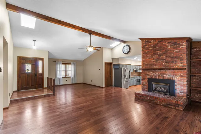 an empty room with wooden floor fireplace and windows