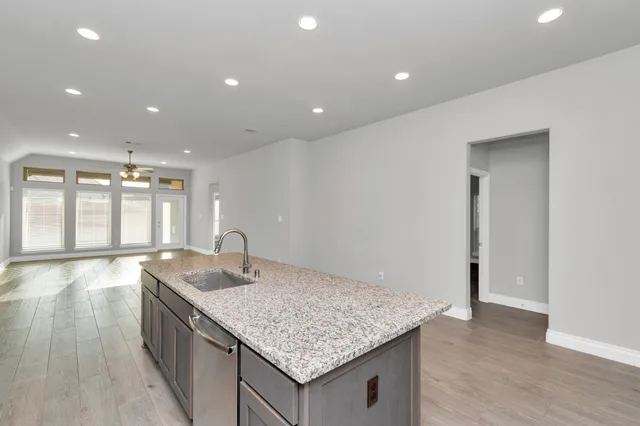 a large kitchen with stainless steel appliances kitchen island granite countertop a large counter top and stove top oven with wooden floor