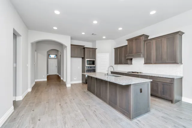 a large kitchen with granite countertop a stove a sink and a microwave