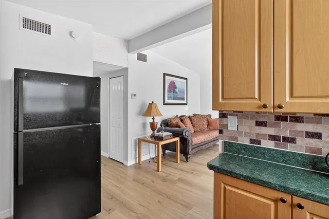 a living room with stainless steel appliances granite countertop furniture and a refrigerator