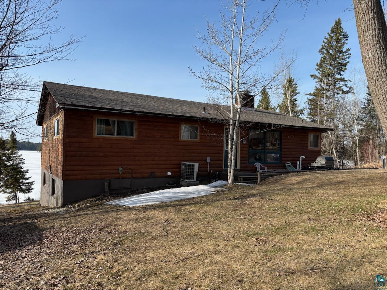 444 Fernberg Road, Unit 11 Ely, MN 55731 - Photo 2 of 19 Back of property featuring cooling unit, a chimney, a lawn, a shingled roof, and a patio