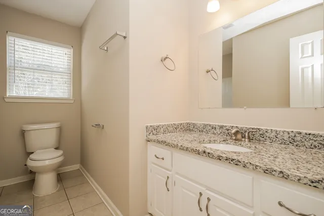 a bathroom with a granite countertop sink a toilet and a mirror