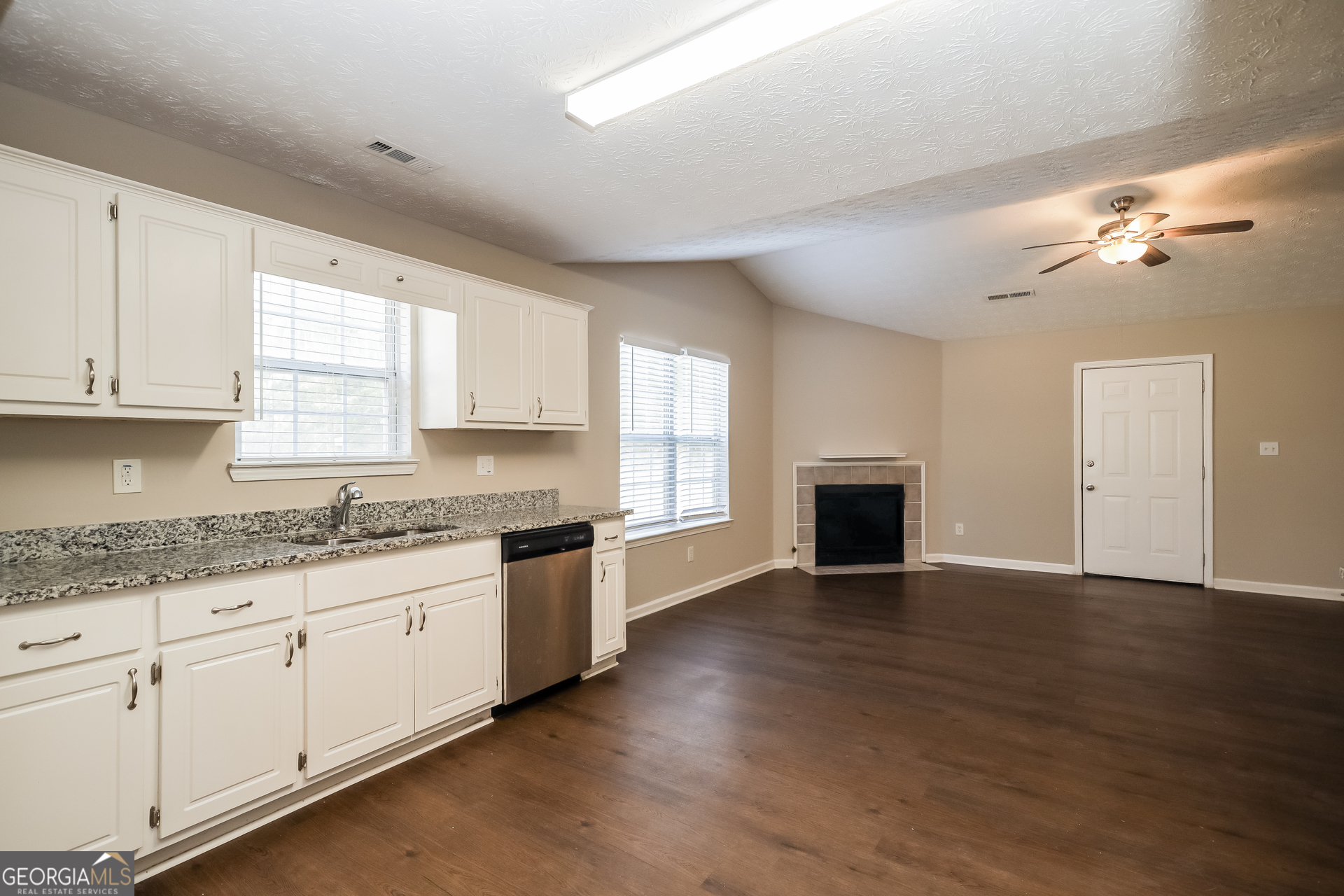 3006 Ryan Road Locust Grove, GA 30248 - Photo 9 of 21 a large kitchen with granite countertop a stove a sink dishwasher and a fireplace with wooden floor