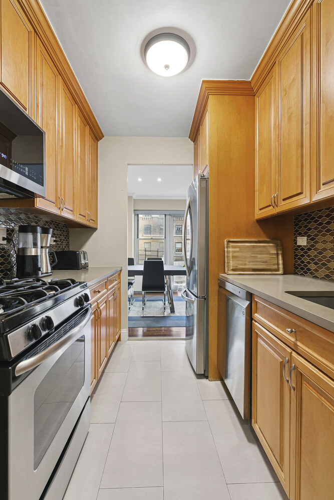 118 East 60th Street, Unit 8CD Manhattan, NY 10022 - Photo 3 of 10 a kitchen with stainless steel appliances granite countertop a stove a sink and a refrigerator
