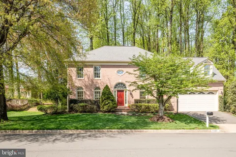 a front view of a house with a yard and a large tree