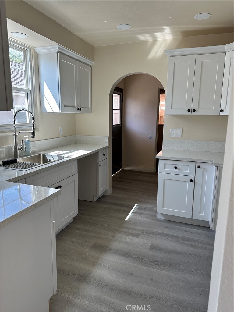 a kitchen with stainless steel appliances granite countertop a sink a stove and white cabinets with wooden floor