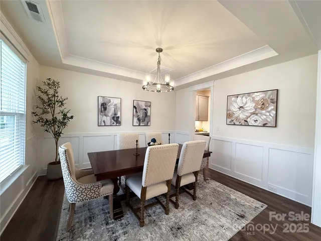 a dining room with wooden floor a chandelier a glass table and windows