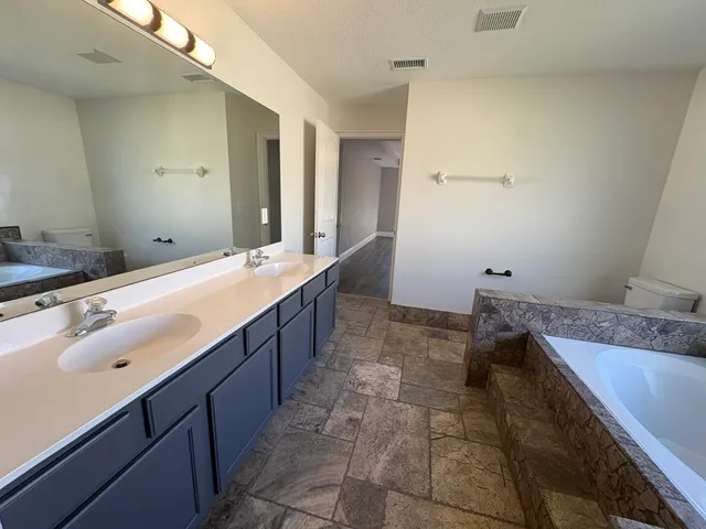a spacious bathroom with a granite countertop sink a mirror and a bathtub