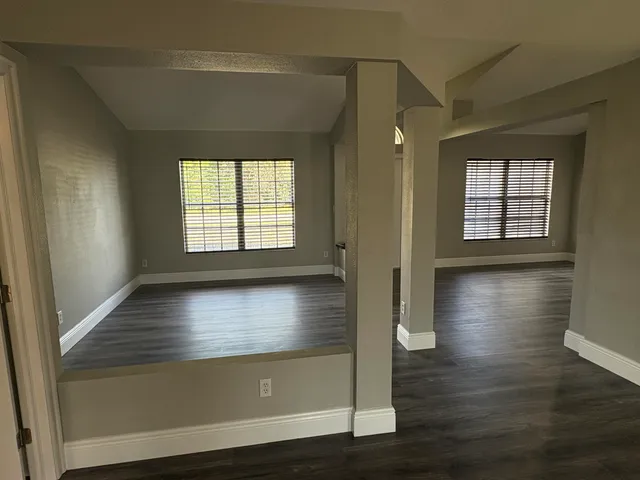 an empty room with wooden floor and windows
