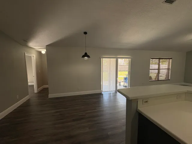 a view of an empty room with window and wooden floor