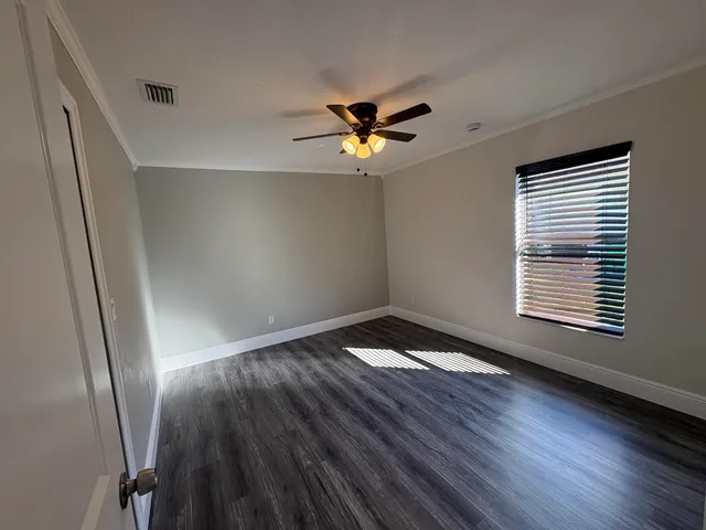 a view of empty room with wooden floor and fan
